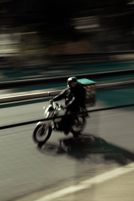 There is no image of flowers or floral arrangements. The image shows a motorcyclist wearing a black helmet and jacket, riding a motorcycle along a city street with a blurred background indicating moti